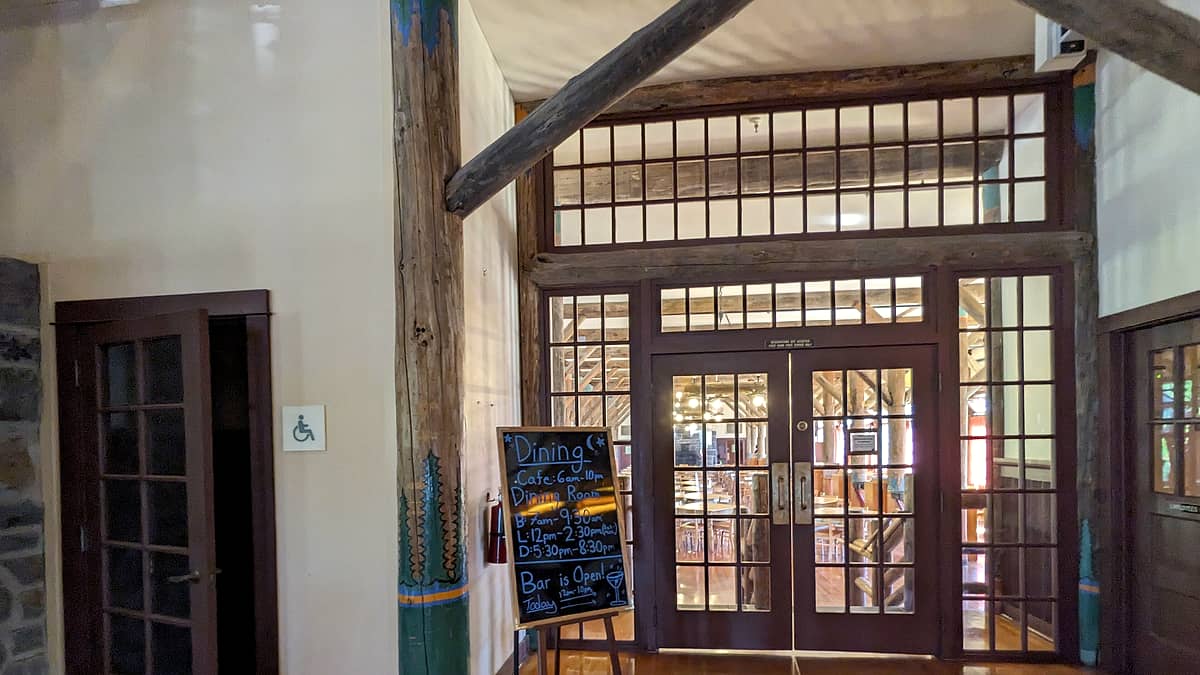 A wooden door standing slightly ajar at the end of a narrow hallway with worn floorboards underfoot